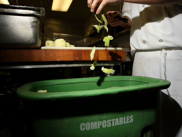 A prep cook at MoMo's restaurant in San Francisco drops apple skins into a food-scrap recycling container in 2009. Composting, a process that converts organic materials into nutrient-rich soil, can help reduce the amount of trash dumped into landfills.