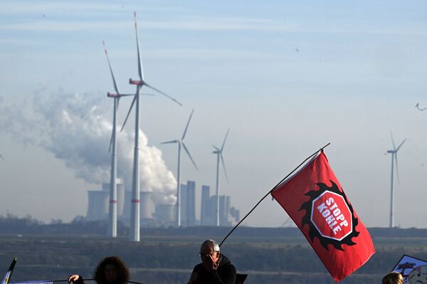 A protester holds a flag reading "stop coal" in front of coal-fired Neurath Power Station, next to the Garzweiler coal mine, in Luetzerath, Germany, on Nov. 12. German energy provider RWE plans to demolish nearby wind turbines to expand the mine. Germany is resurrecting 20 coal-fired power plants — or extending them past their closing dates — to ensure the country has enough energy.