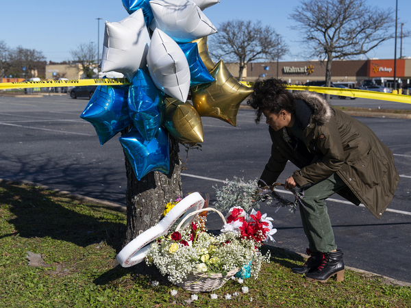 Shyleana Sausedo-Day, from Portsmouth, Va., places flowers near the scene of a mass shooting at a Walmart, Wednesday in Chesapeake, Va.