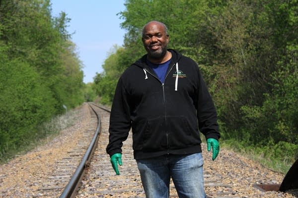 A man stands along train tracks