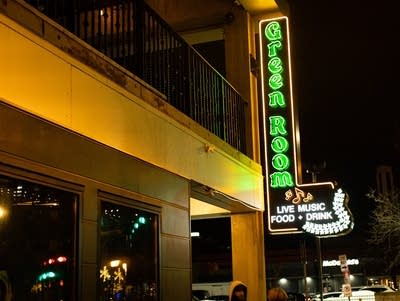 Outside the venue, a vertical neon marquee says, "Green Room"