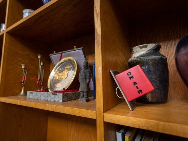 A red "on air" light sits on a shelf with other artifacts