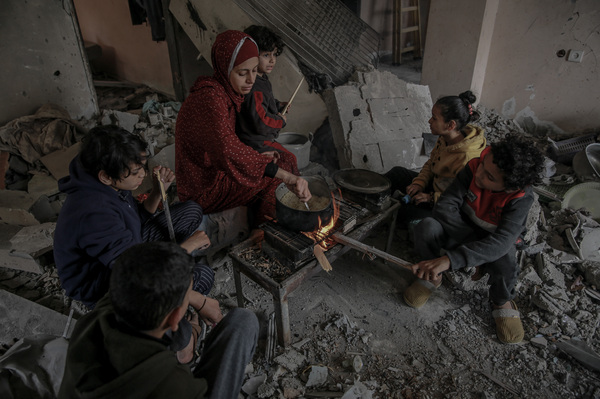 Nermeen Tafesh prepares her family's only meal of the day with her five children in their destroyed home in Hayy al-Nasr.