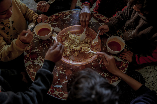 Tafesh and her children eat a small amount of rice and sauce. This is their only meal of the day.