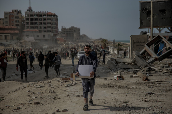 A Palestinian man carries a box of aid on Al Rashid Street from one of the rare aid convoys that reached northern Gaza via land crossing, on March 6.