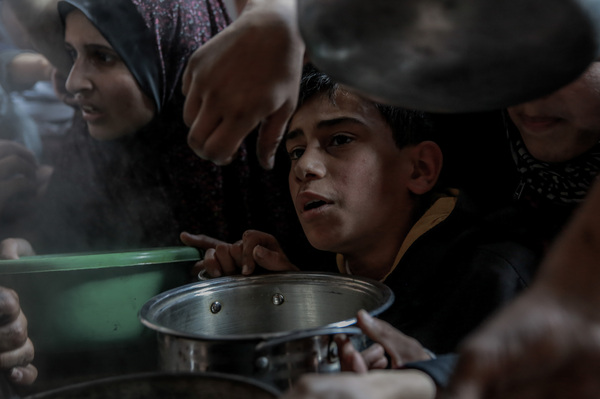 A Palestinian boy waits with his pot among a crowd in Beit Lahia, in northern Gaza, while trying to get a small amount of soup from one of the few soup kitchens, on Feb. 26.