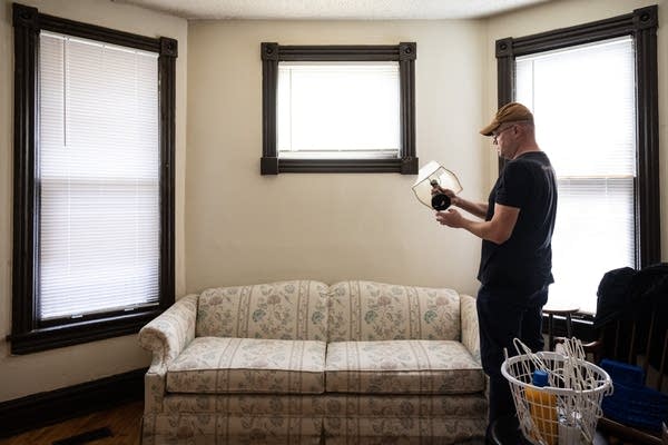 A man holds a lamp in a living room