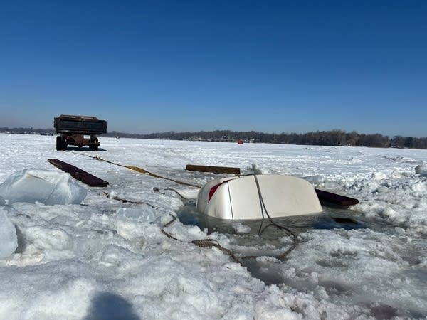 The rear end of a white car sticks out of the ice.