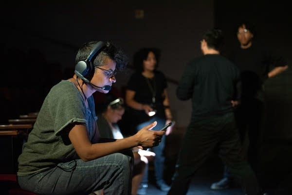 person with headset sits looking at a screen