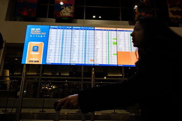 A person walks by an arrival and departure board at Boston's Logan Airport on Dec. 23, 2024.