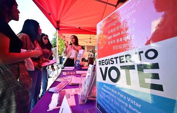 Potential young voters get information at a voter registration desk at California State University, Los Angeles, on Oct. 22, 2024. The Republican-backed SAVE Act would add documentary proof-of-citizenship requirements to voter registration.