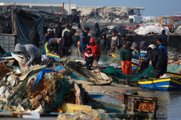 Palestinians gather with fishermen at the port of Gaza City on Sunday. Israeli bombardment over more than 15 months of war between Israel and Hamas has destroyed most of the boats in the harbor, wrecking the fishermen's ability to make a living and provide food to people in Gaza.