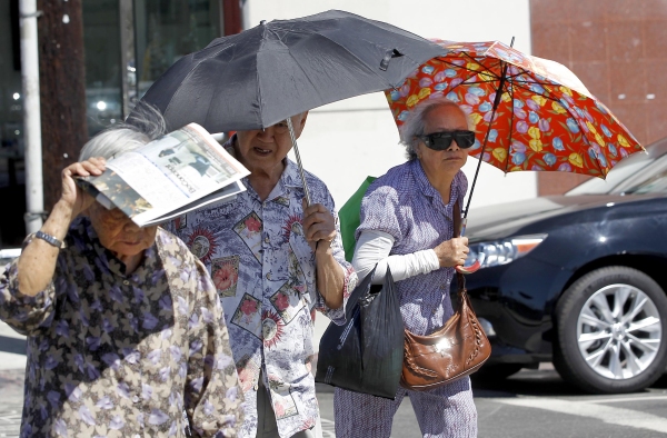 Older people in Los Angeles's Chinatown neighborhood shade themselves from the beating sun. Exposure to heat can change the way people's genes work, potentially leading to long-term health impacts. Climate change is making heat waves more intense and long-lasting in many parts of the U.S.