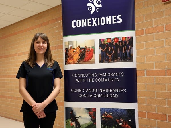 a woman stands next to a sign