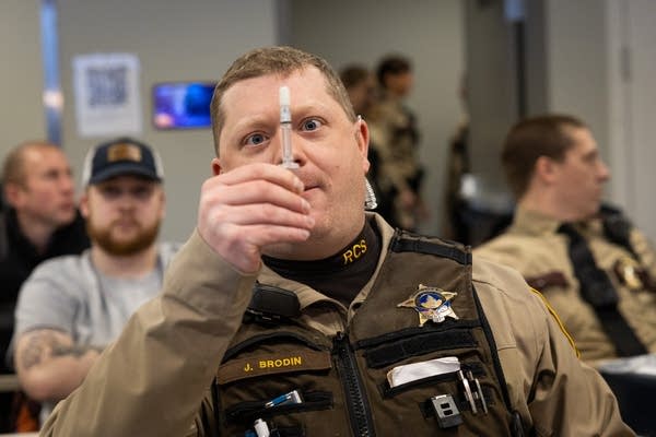 A sheriff holds up a vial of saliva