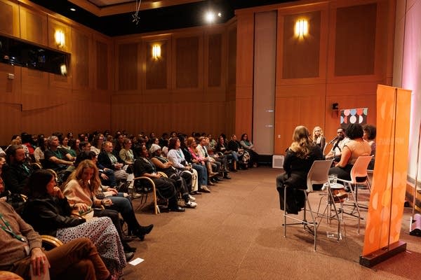 People watch speakers on stage