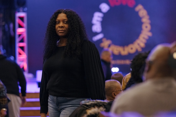 Certina Robinson wears jeans and a black shirt. She's standing in an auditorium. 