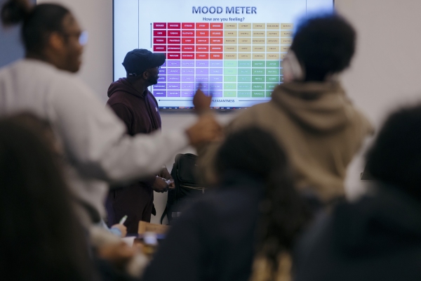 On a big screen at the front of a large room is a colorful chart with the headline "Mood Meter."