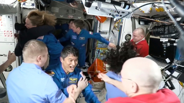 This image made from video by NASA shows astronauts, including Takuya Onishi, center, greeting each other after the SpaceX capsule docked with the International Space Station, on Sunday.