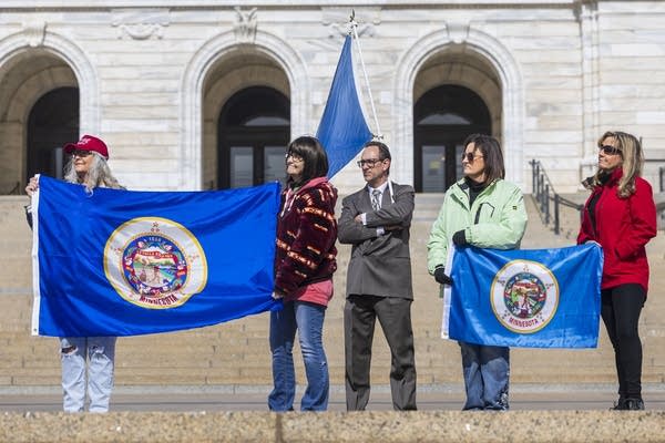 a group of people hold the old minnesota flag