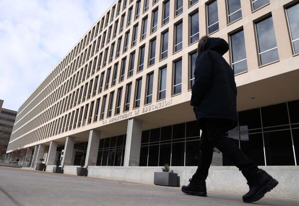 A man walks past the U.S. Department of Education building in Washington, D.C., on February 7. The building is about six stories tall and has rows of tall narrow windows.