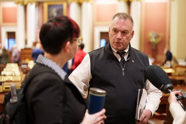 A man holds papers and talks