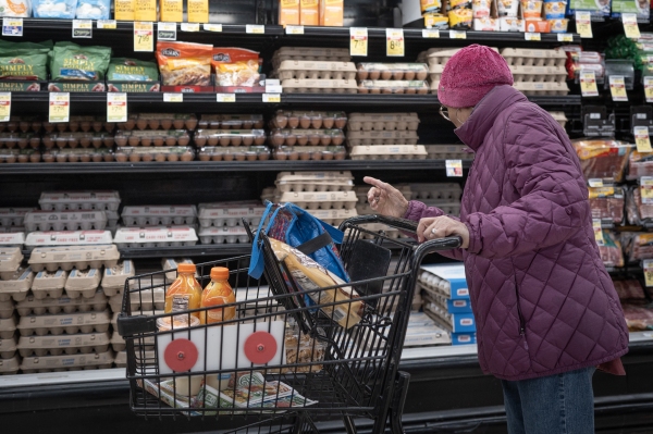 A customer shops for eggs at a grocery store on March 12 in Chicago. Wholesale egg prices are going down, but it could take several days before grocery prices follow suit.