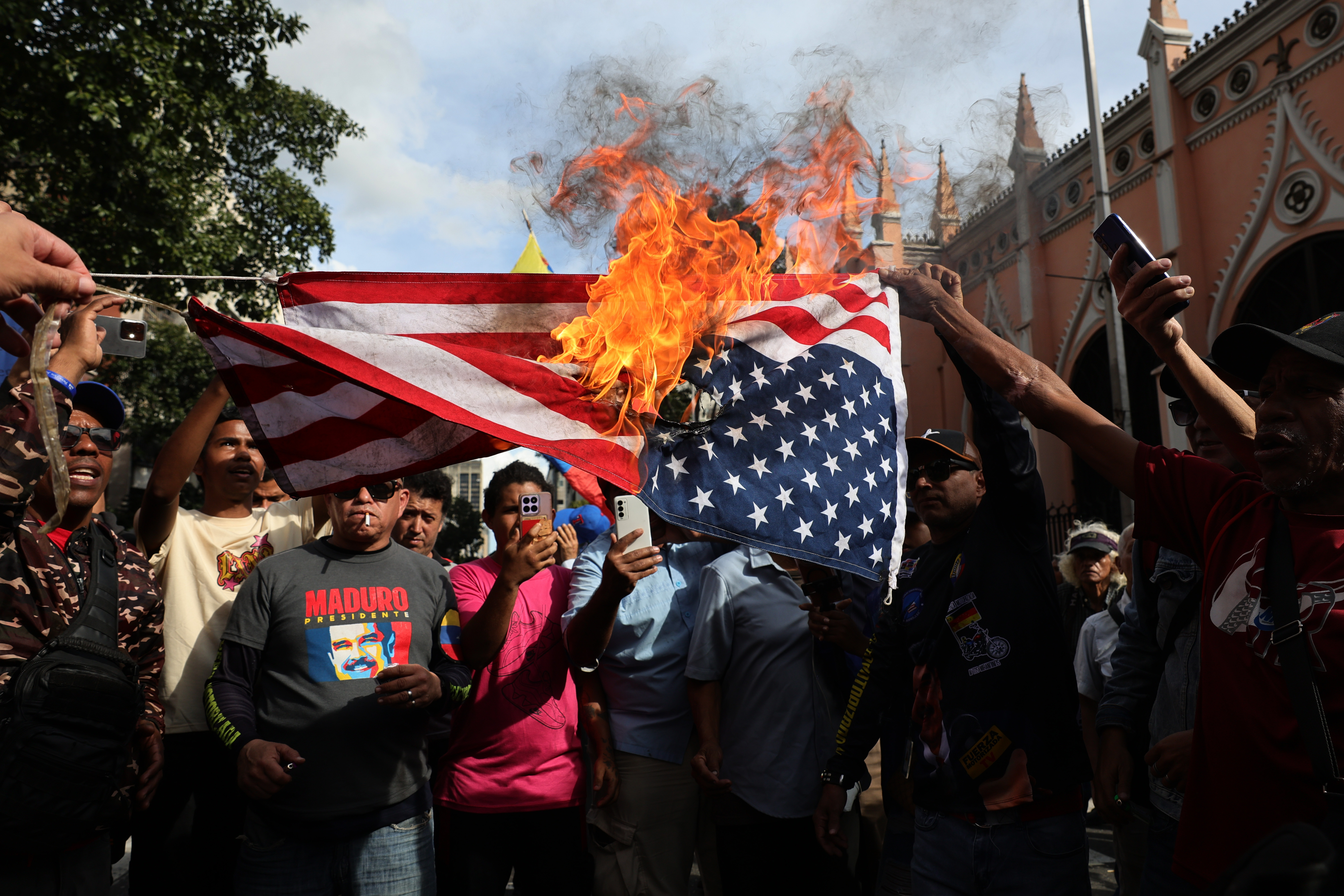 Supporters of Nicolas Maduro burn a United States flag.