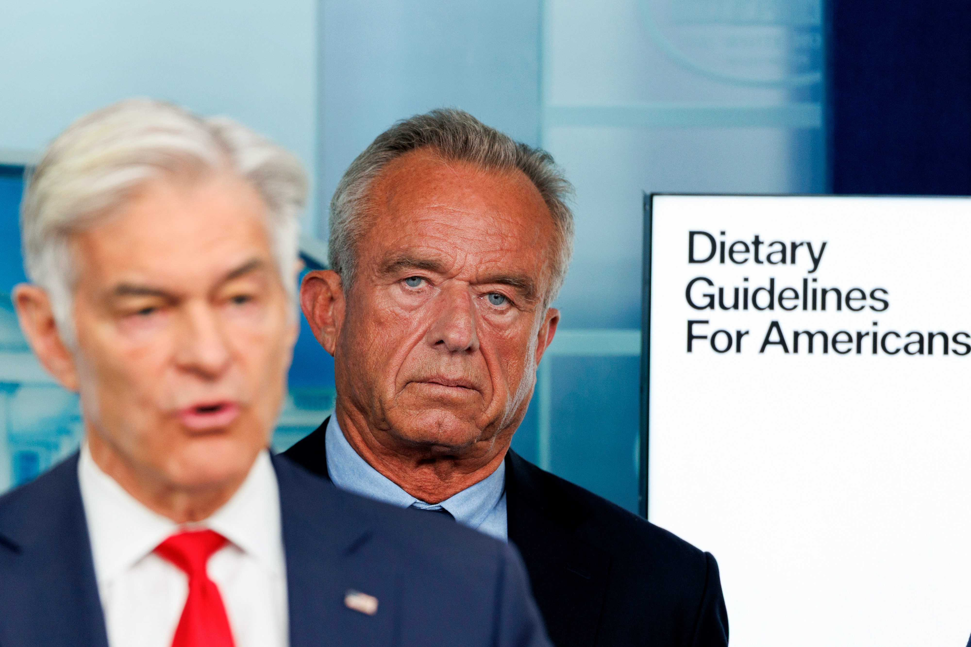 Mehmet Oz and RFK Jr. stand by a sign that reads Dietary Guidelines for Americans