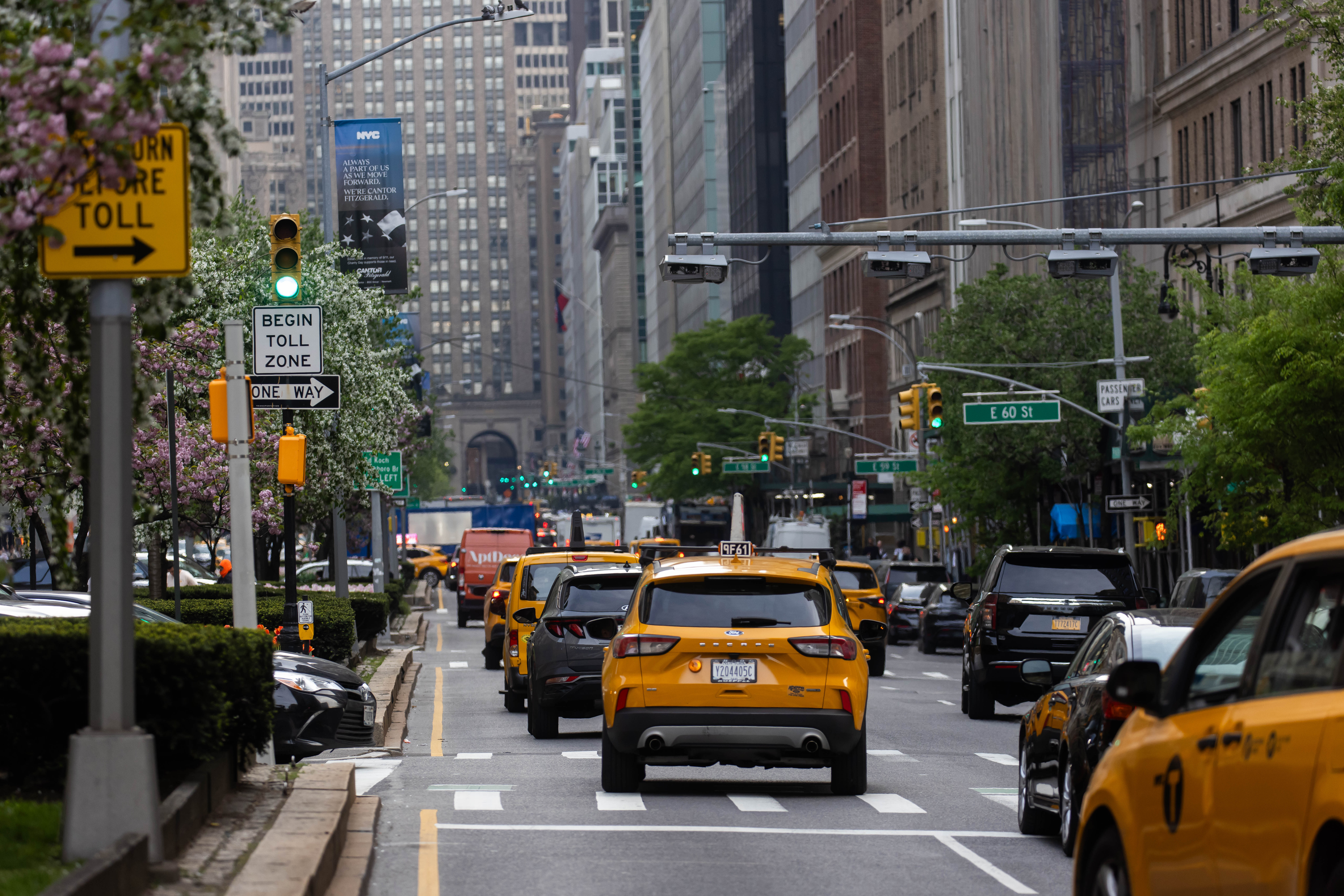 A New York city street with yellow cabs, other cars, and buildings.