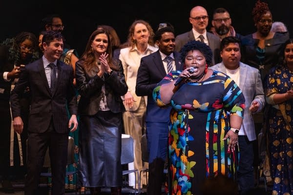 A Black woman sings on stage