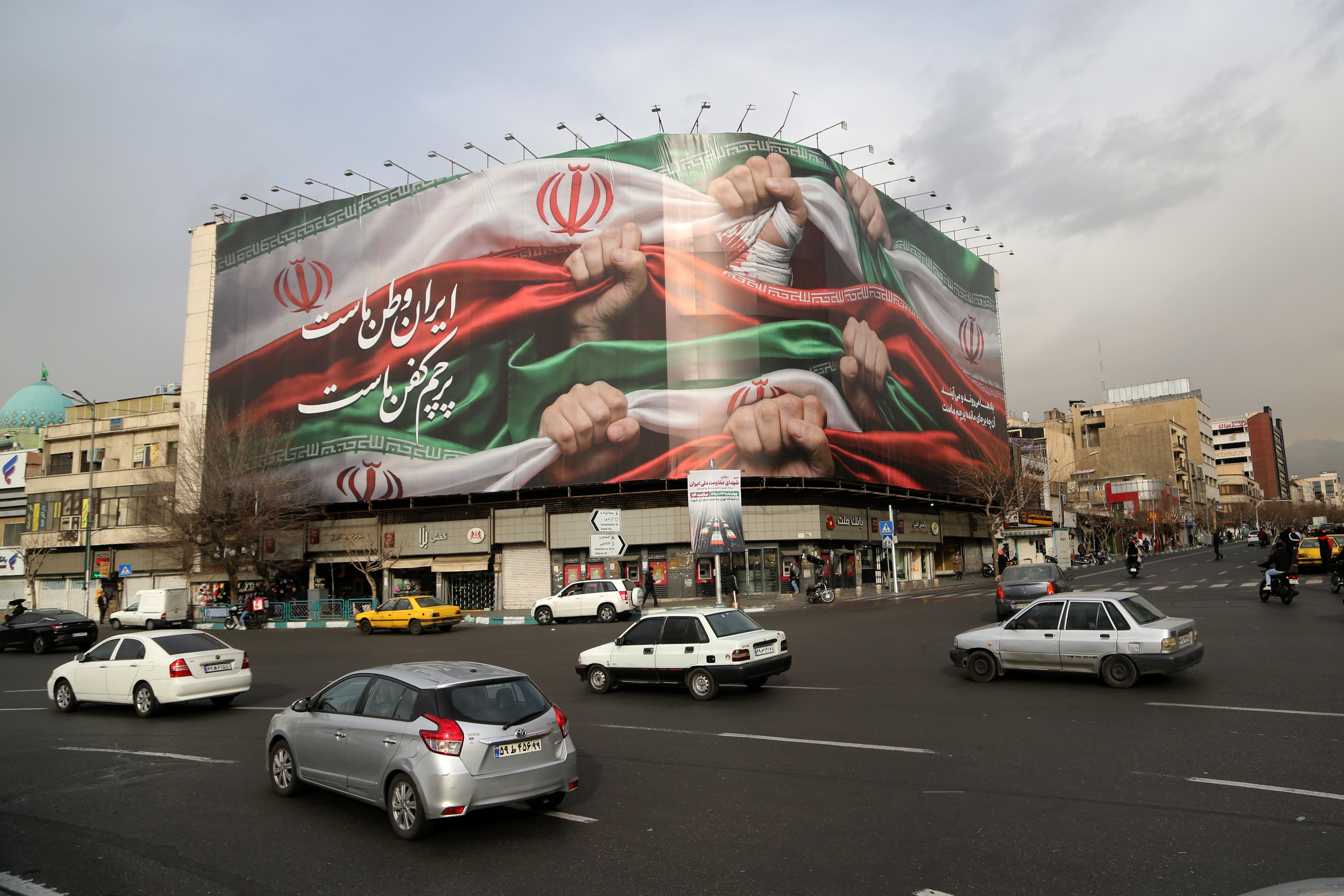 Banner of fists holding Iranian flag over a busy street