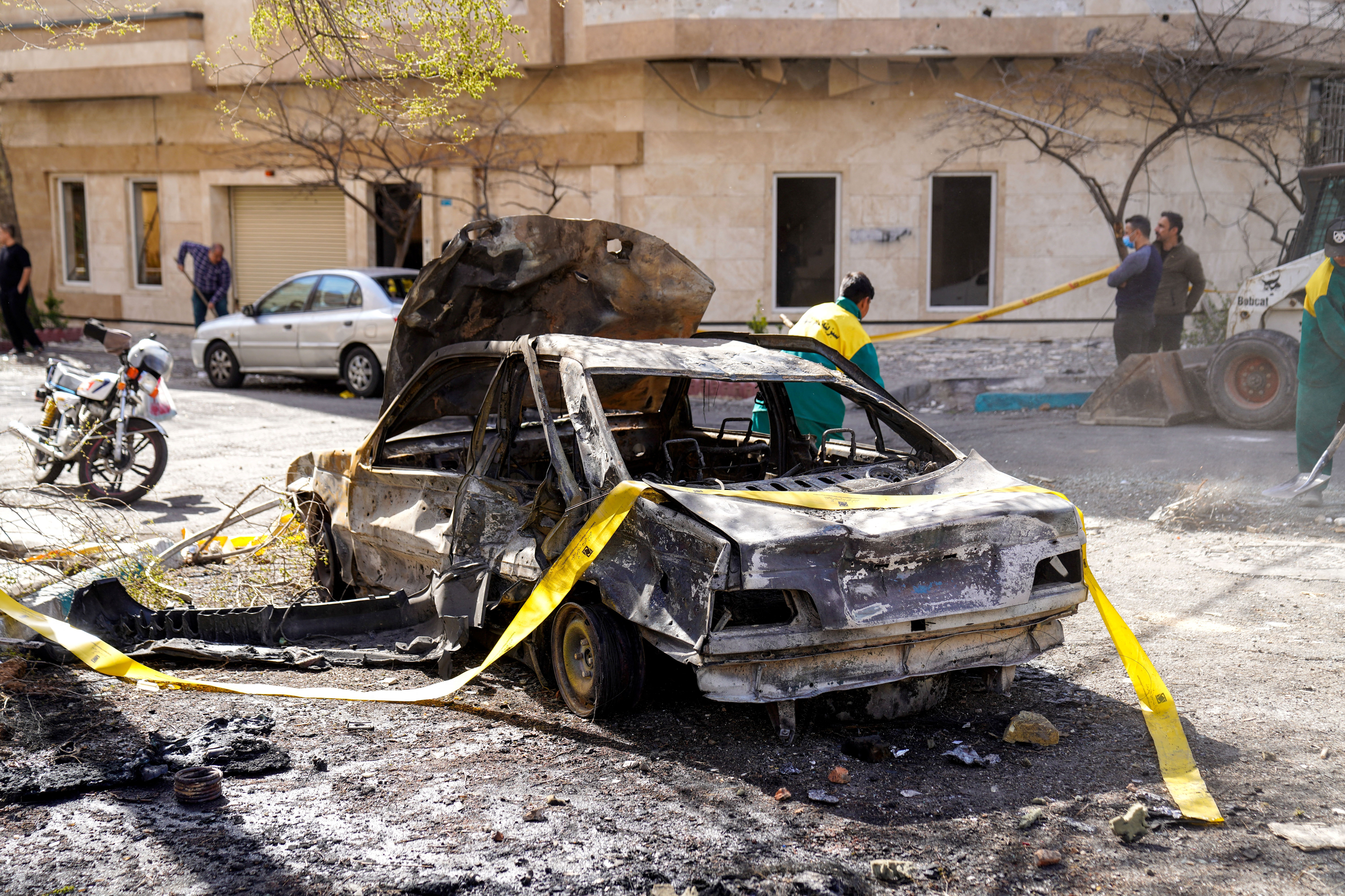 Yellow tape drapes over a burned-out car in Tehran.