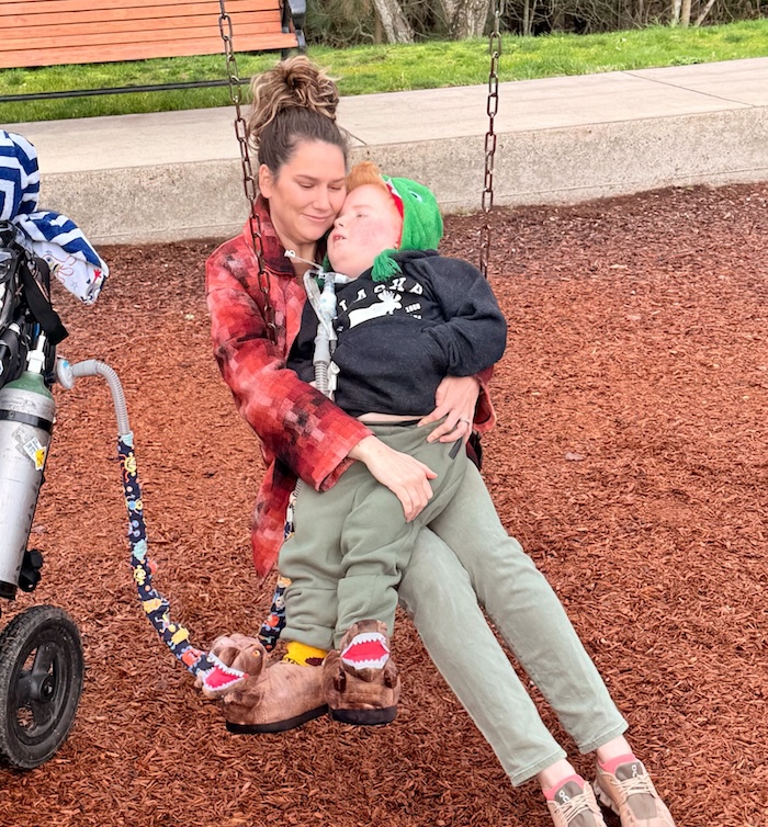 A white woman on a swing with her disabled son.