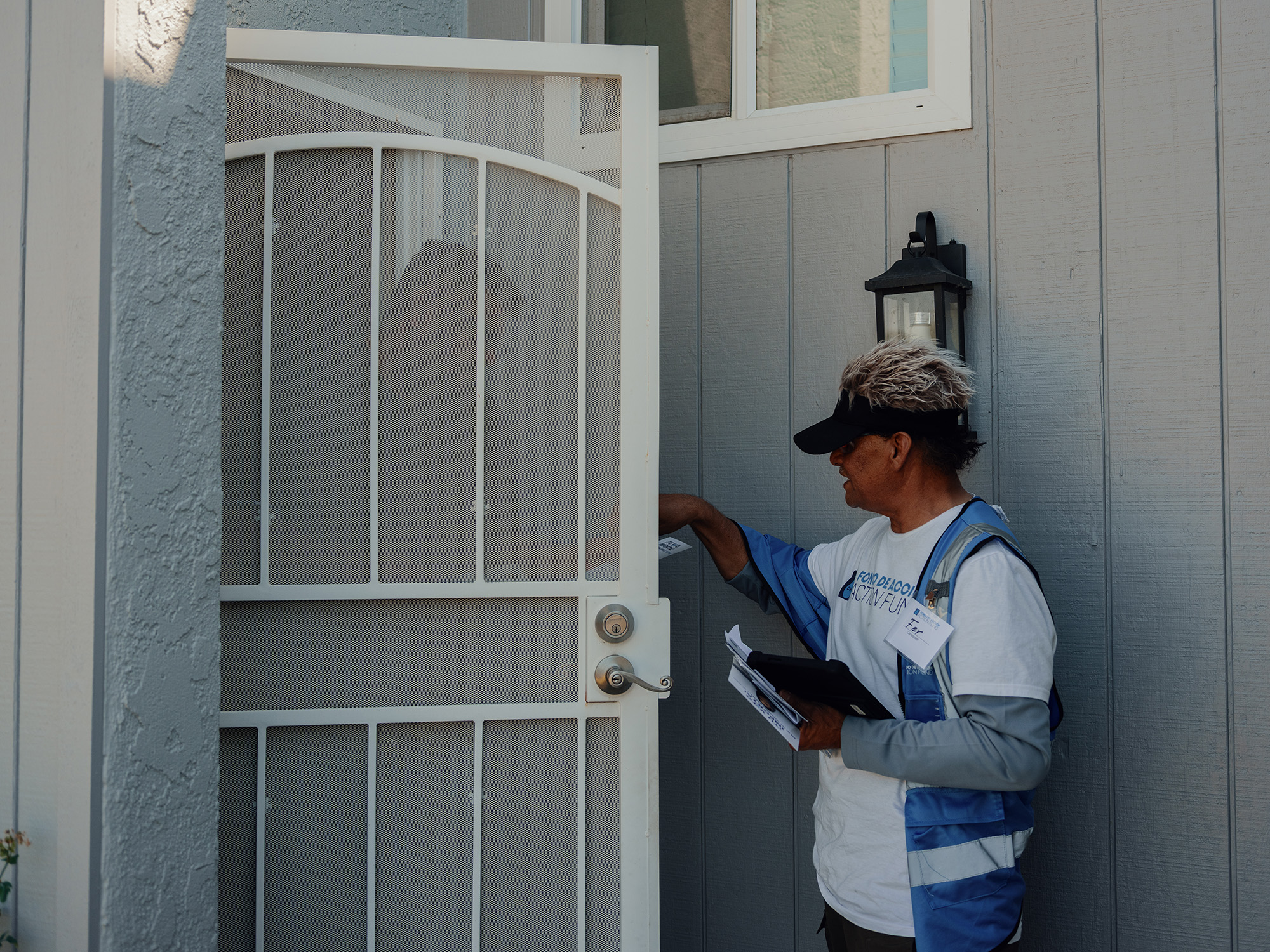 A man hands a flyer to a person at their front door.