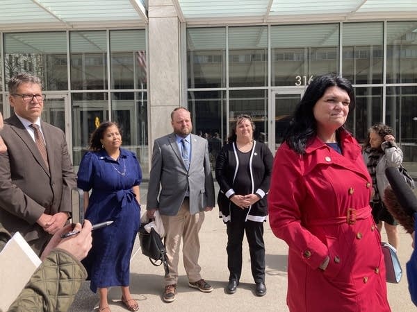 woman speaking to reporters outside of a building