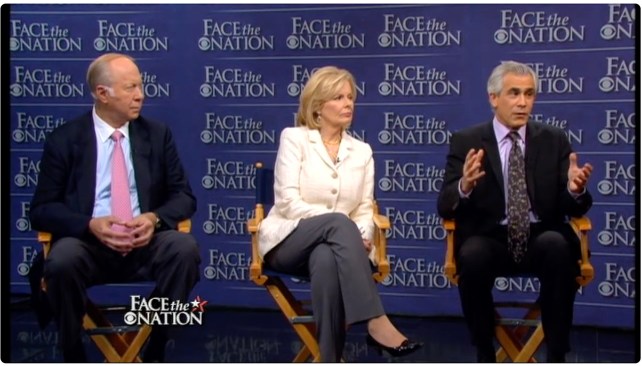 A woman sits between two men on a TV set. All three sit in director's chairs and the background has repeating logos for "Face the Nation."