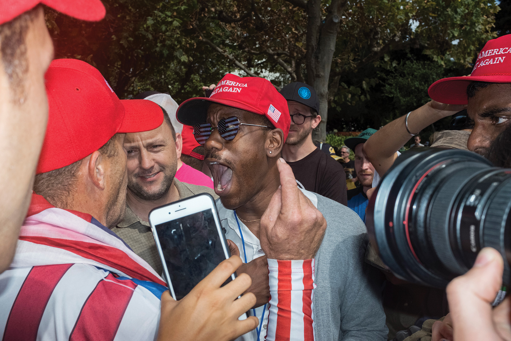 Men in red MAGA baseball caps stand close together and appear to be screaming at one another.