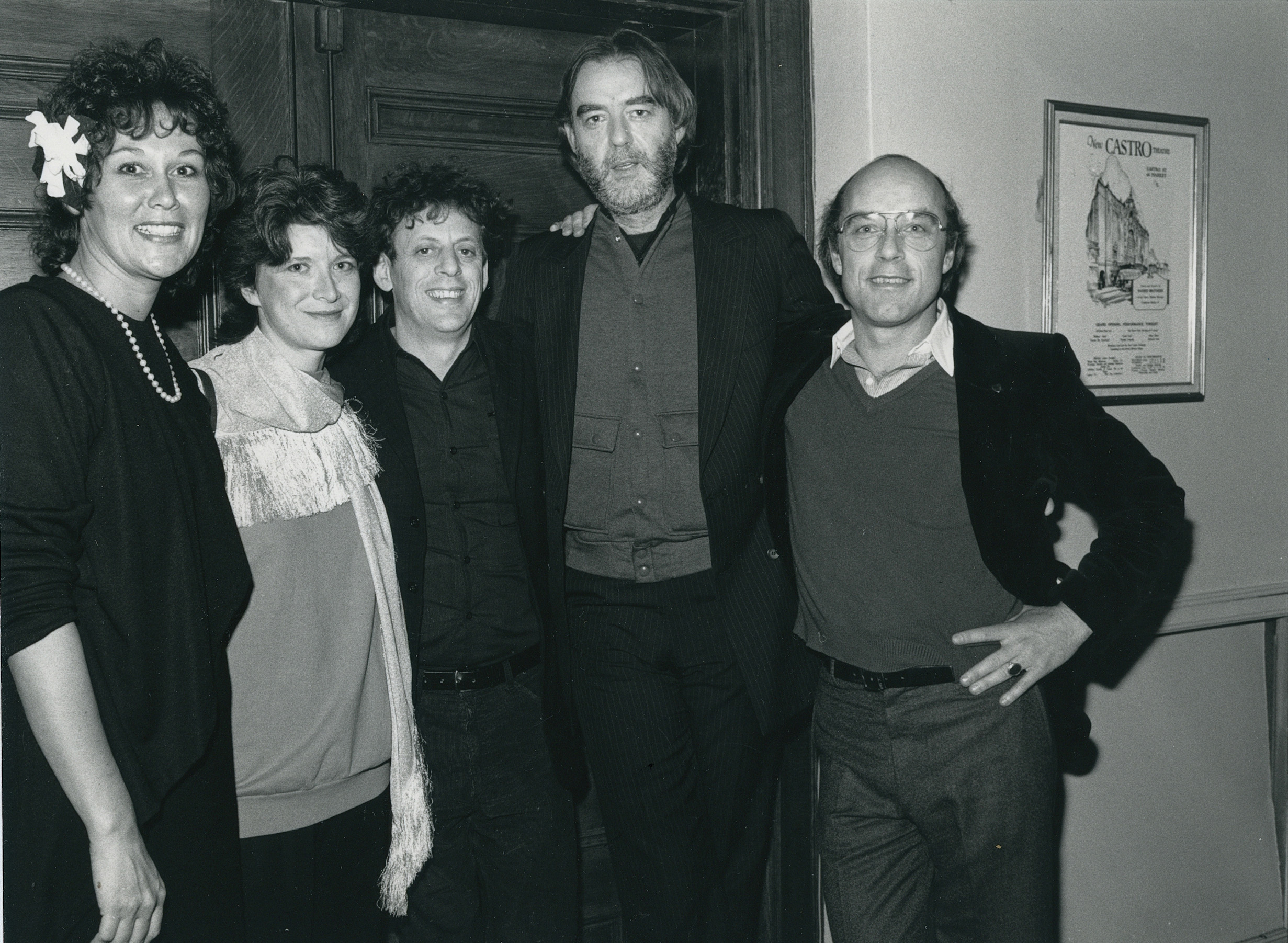 Five people stand side by side, arms around one another, to pose for a group photo.