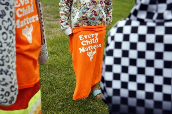 child holds orange shirt 