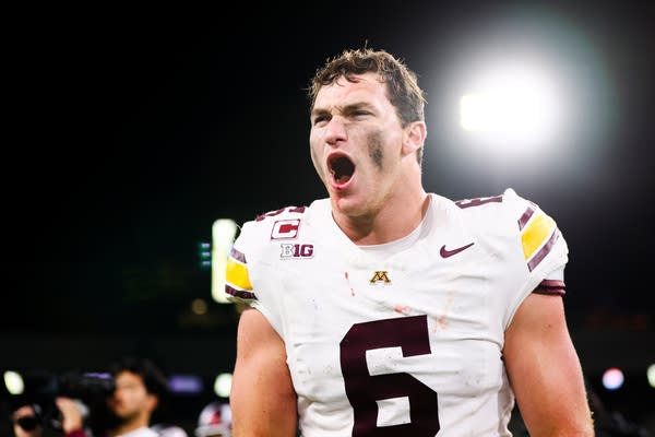 A football player cheers in celebration as blood drips from his mouth.