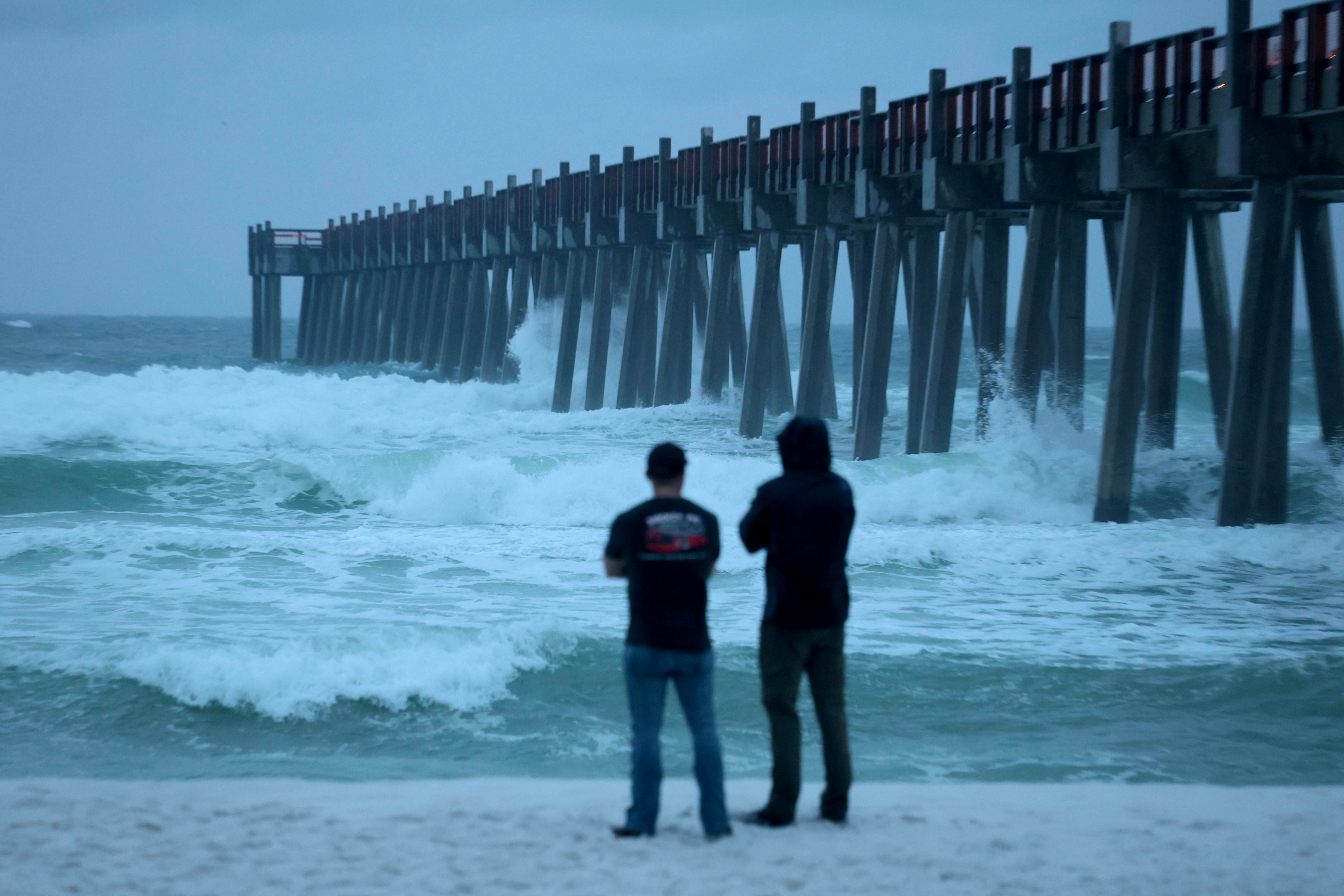 People look out at the waves churning in the ocean as Hurricane Isaias approaches.