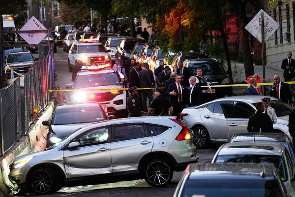 A crime scene with damaged cars is roped off by police tape on a busy city street.