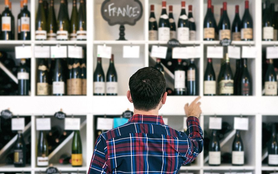 Owner/salesperson and customers inside a small, local wine shop.