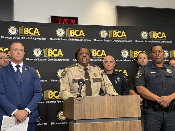 A county sheriff speaks at a podium surrounded by other law enforcement officers.