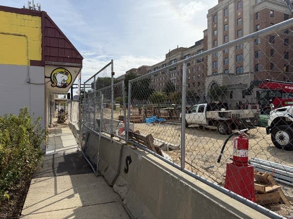 A store front is nearly blocked with construction barriers.