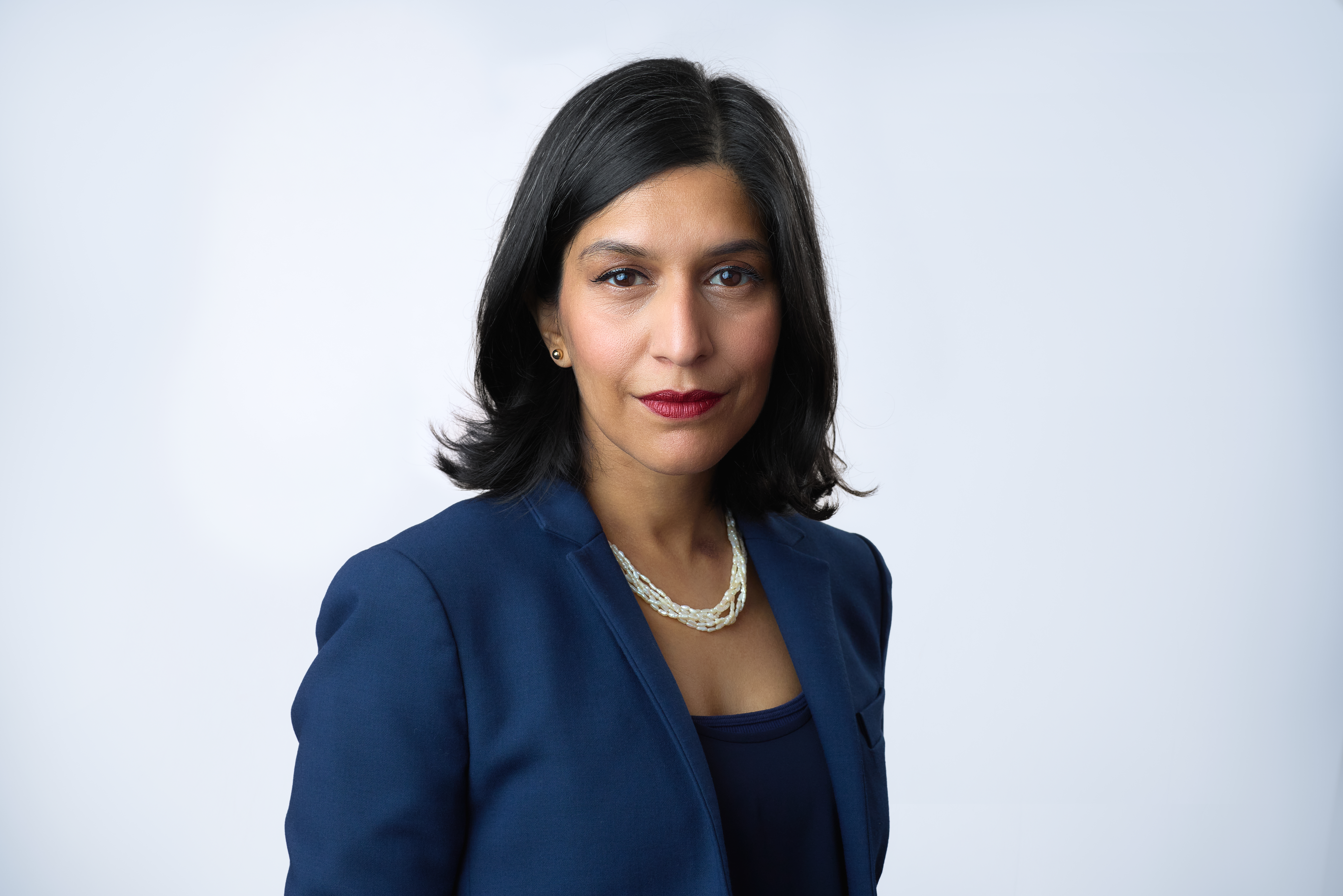 A headshot of a woman wearing a navy blazer
