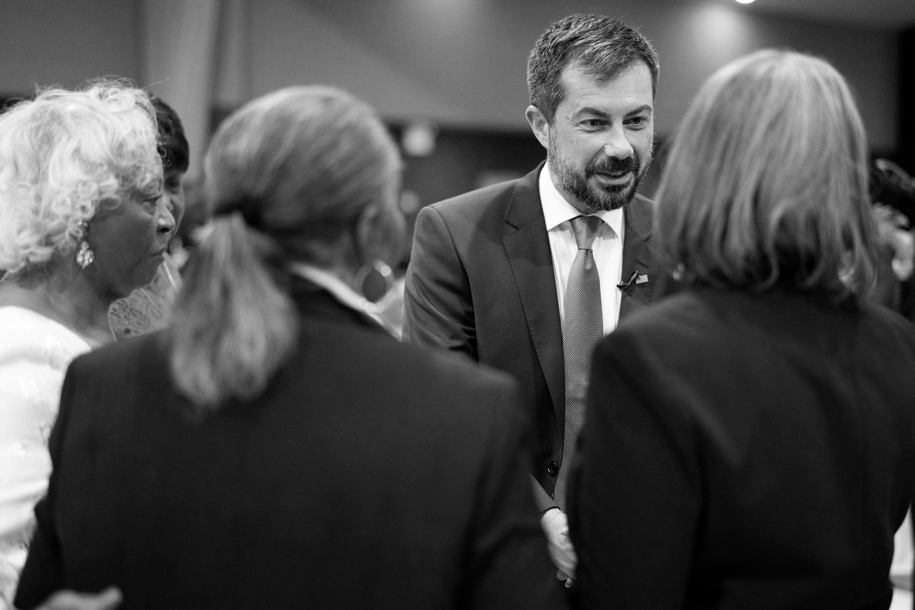 Pete Buttigieg smiles as he meets several women in a church setting