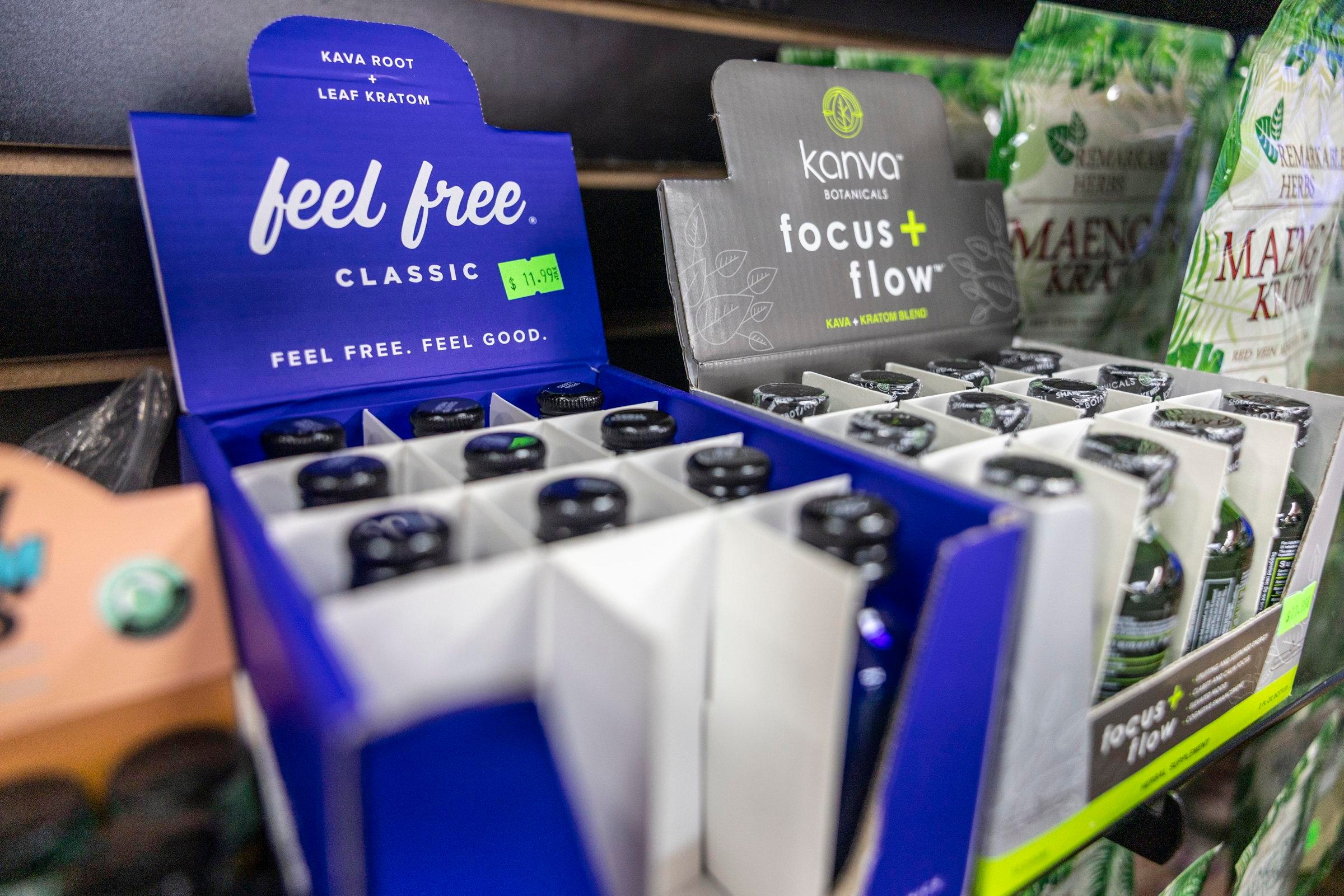 Two products containing the drug kratom are seen packaged in small bottles on a shelf.