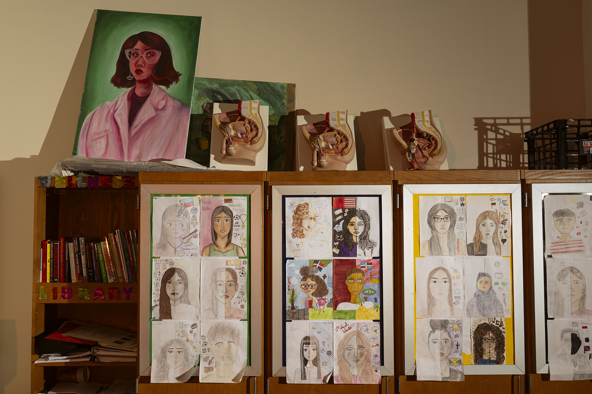 Cabinet with student drawings taped to the front and anatomical models on top.
